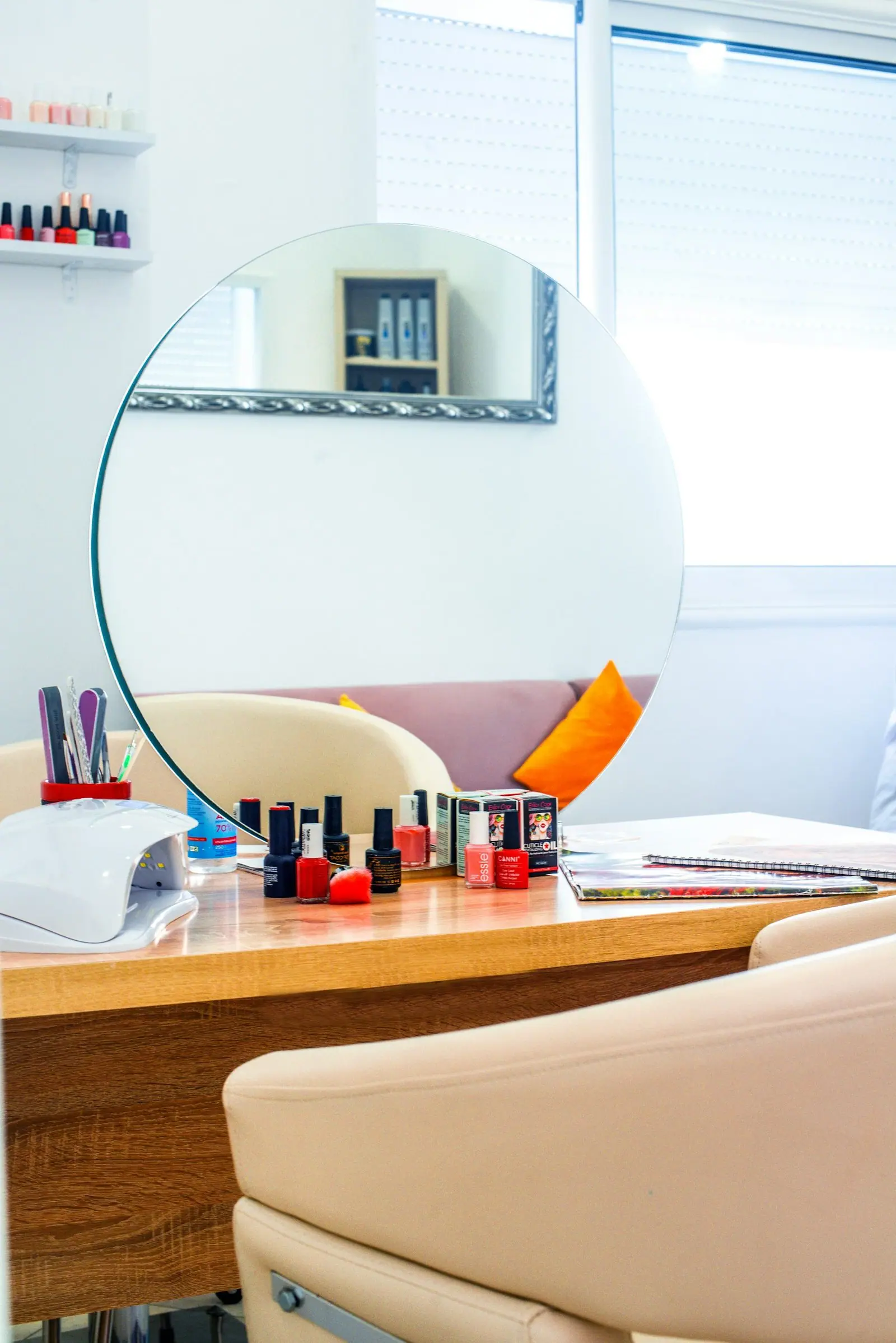 Stanowisko manicure z okrągłym lustrem, lakierami i beżowym fotelem